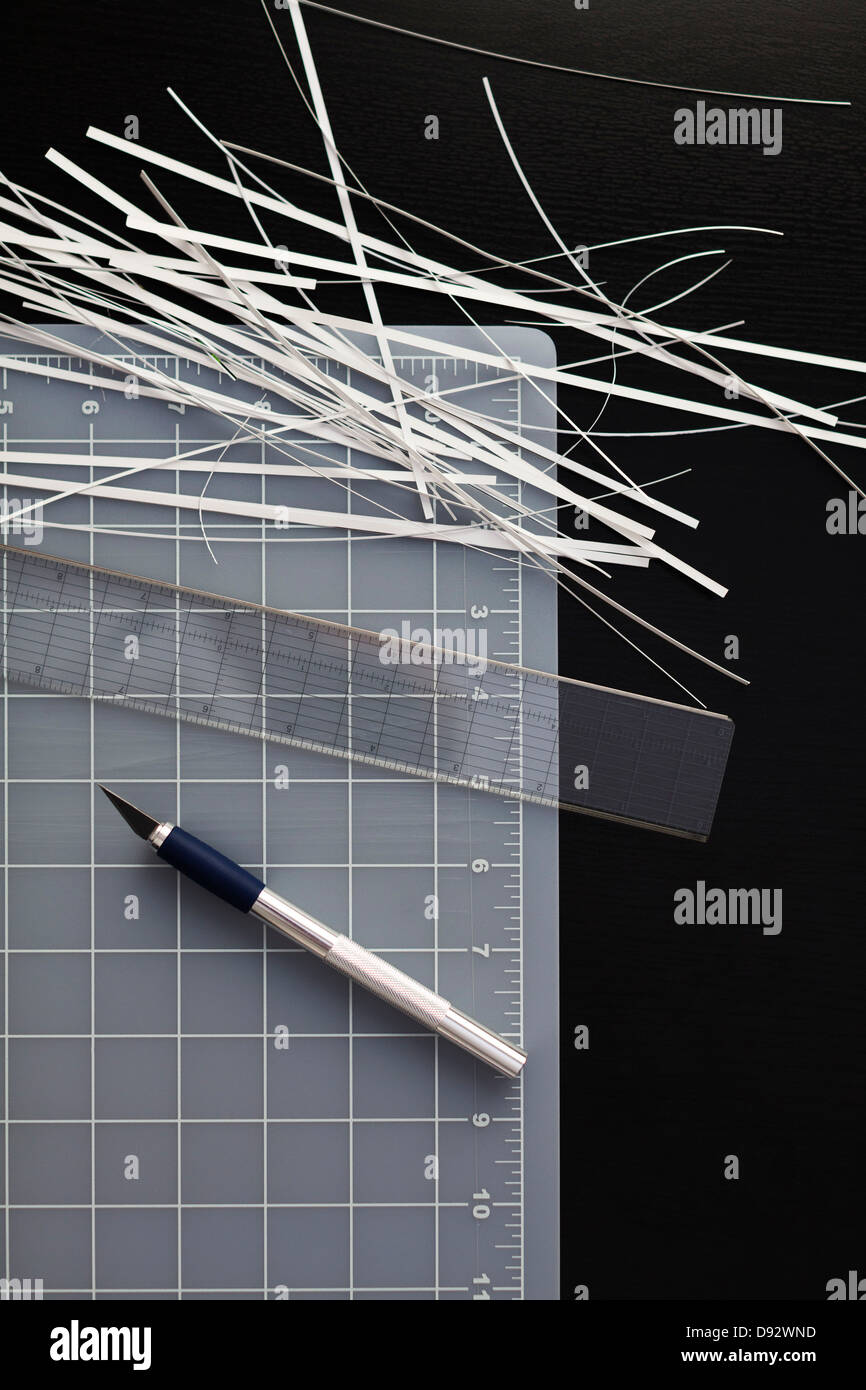 A cutting mat with shredded paper, ruler and utility knife on black background Stock Photo