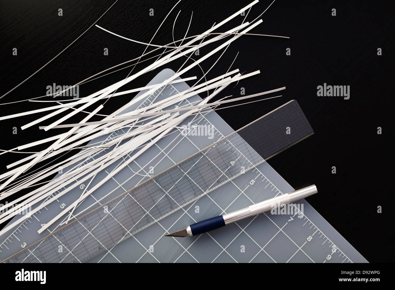 Corner of a cutting mat with shredded paper, ruler and utility knife on black background Stock Photo