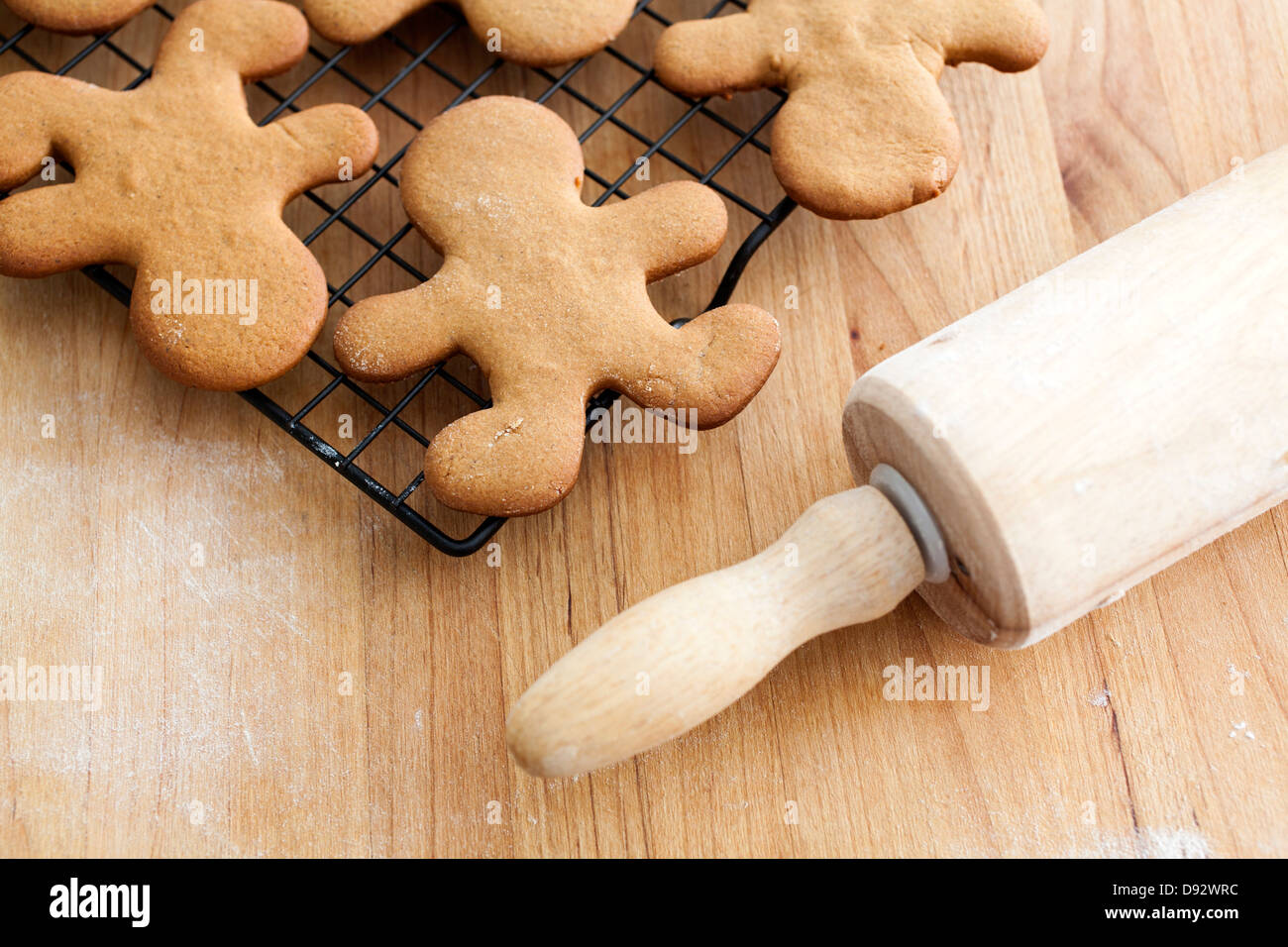 Gingerbread man cookies cooling on a rack next to a rolling pin Stock Photo