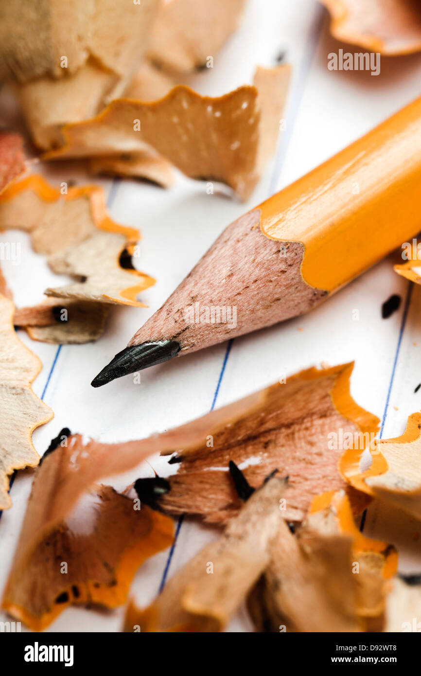A pencil and pencil shavings atop lined notebook paper, extreme close up Stock Photo