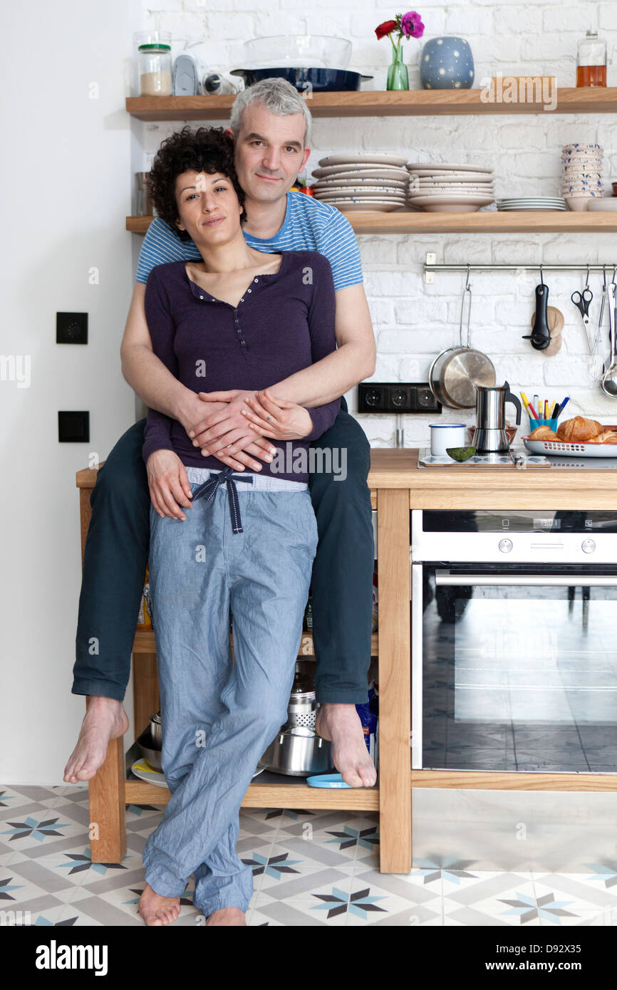 An affectionate smiling mixed age couple in their kitchen Stock Photo