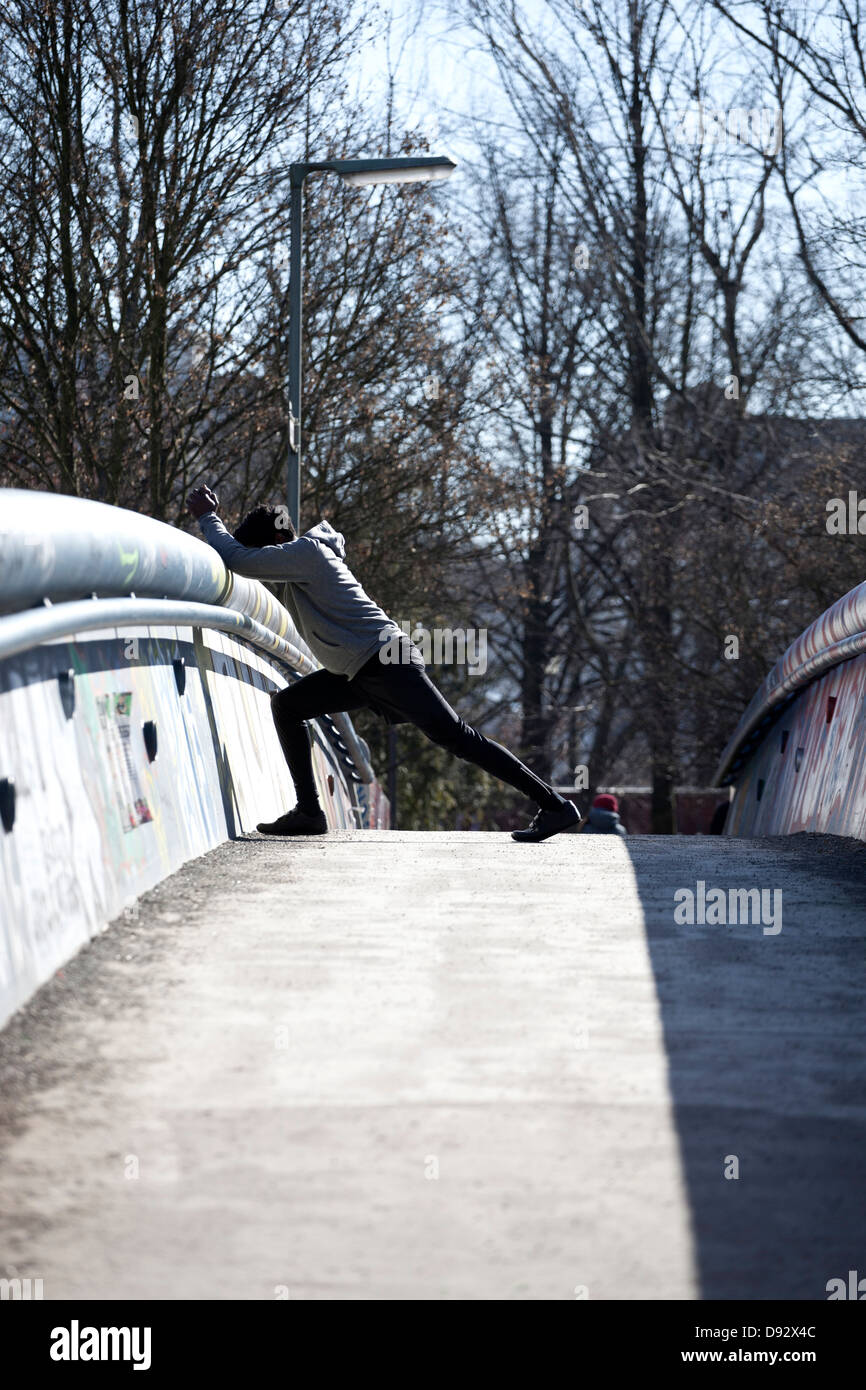 A young man doing a stretching lunge on a bridge Stock Photo - Alamy