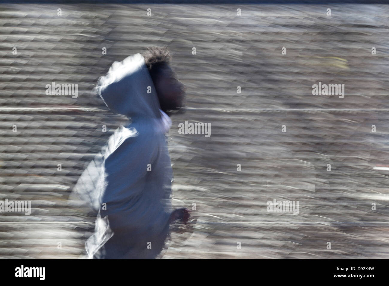A young man jogging in front of a chain link fence Stock Photo