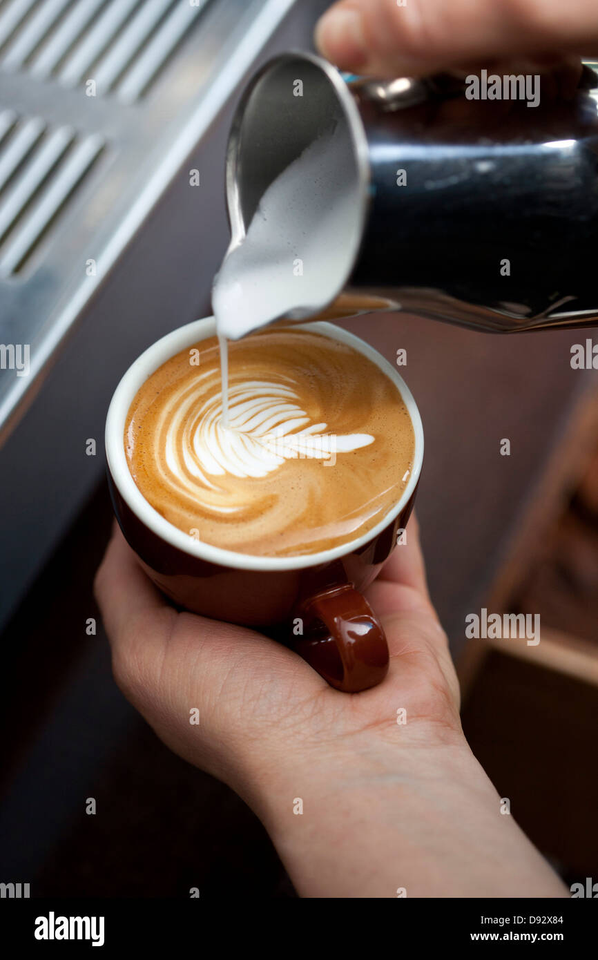 A barista decorating milk froth with a floral pattern Stock Photo