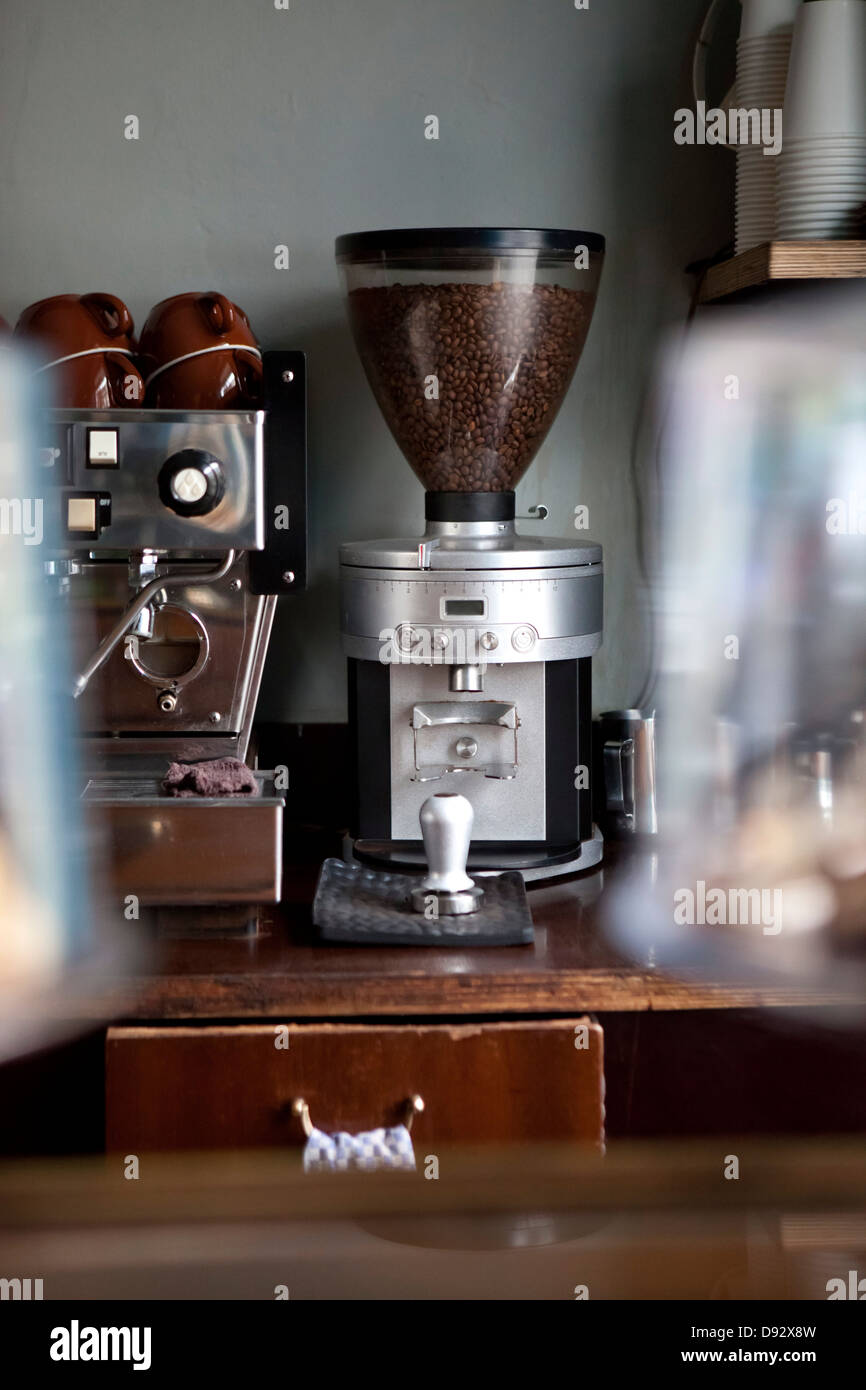 An coffee bean grinder next to an espresso maker in a coffee shop Stock