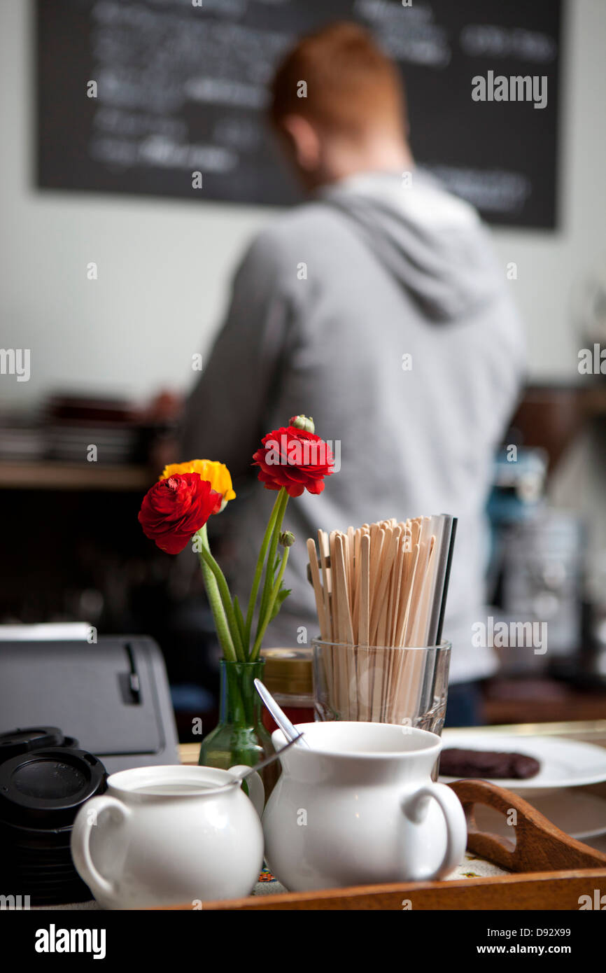 Close-up of condiments at a cafe with barista in background Stock Photo
