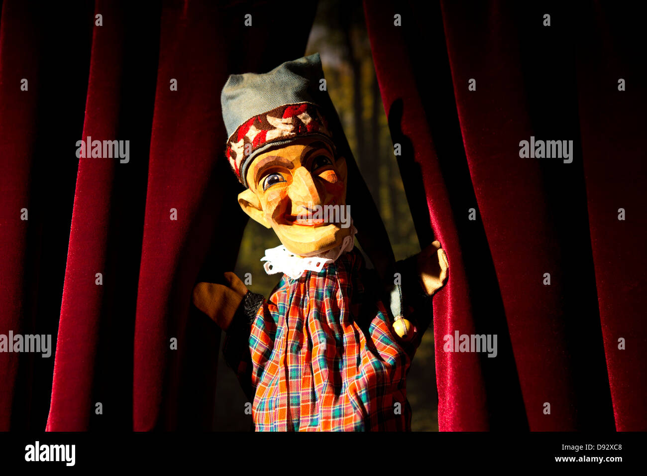 Punch from the classic puppet show Punch and Judy parting the curtains on stage Stock Photo