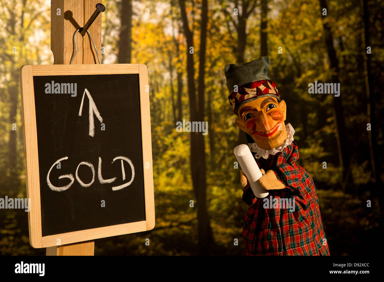 Punch from the Punch and Judy standing next to a board with Gold written on it Stock Photo