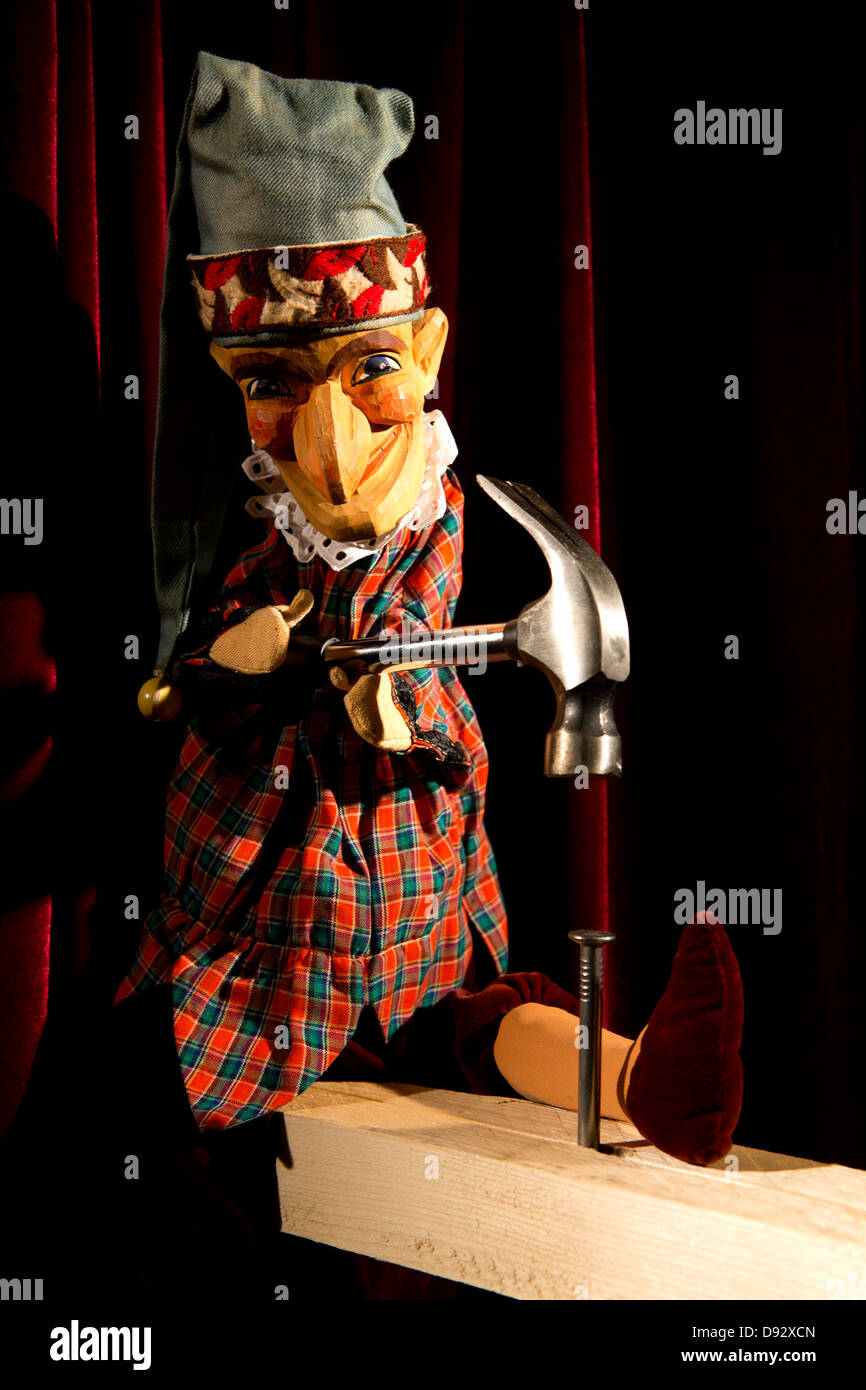 Punch form the puppet show Punch and Judy hammering a nail on stage Stock Photo