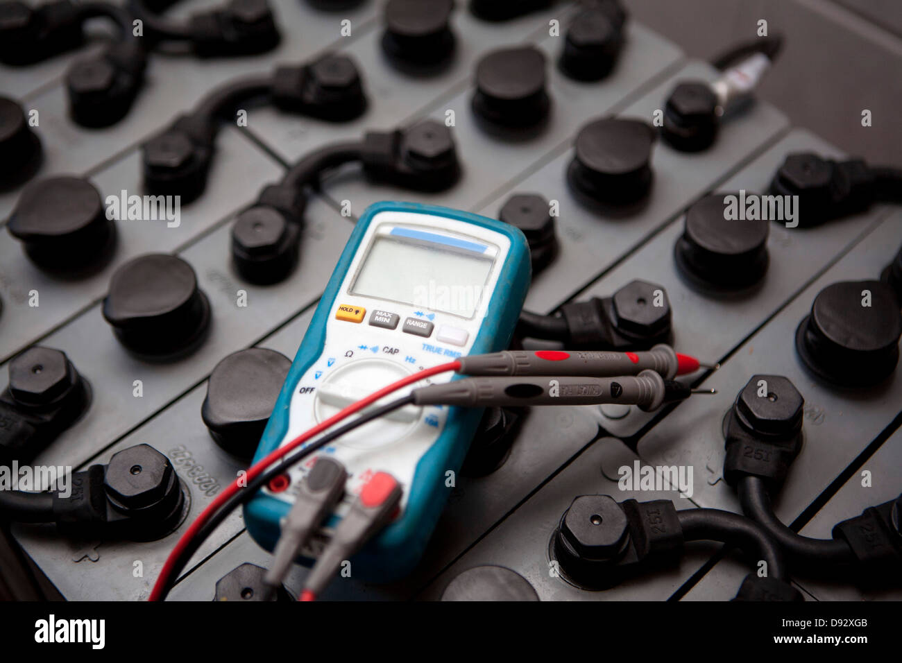 A multimeter lying on top of a battery used in solar powered energy Stock Photo