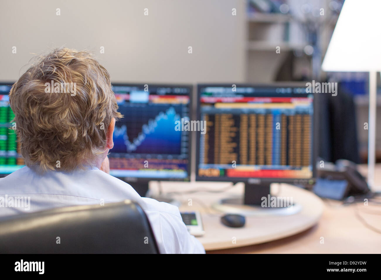 Stock Broker At His Office Desk With Stock Market And Stock