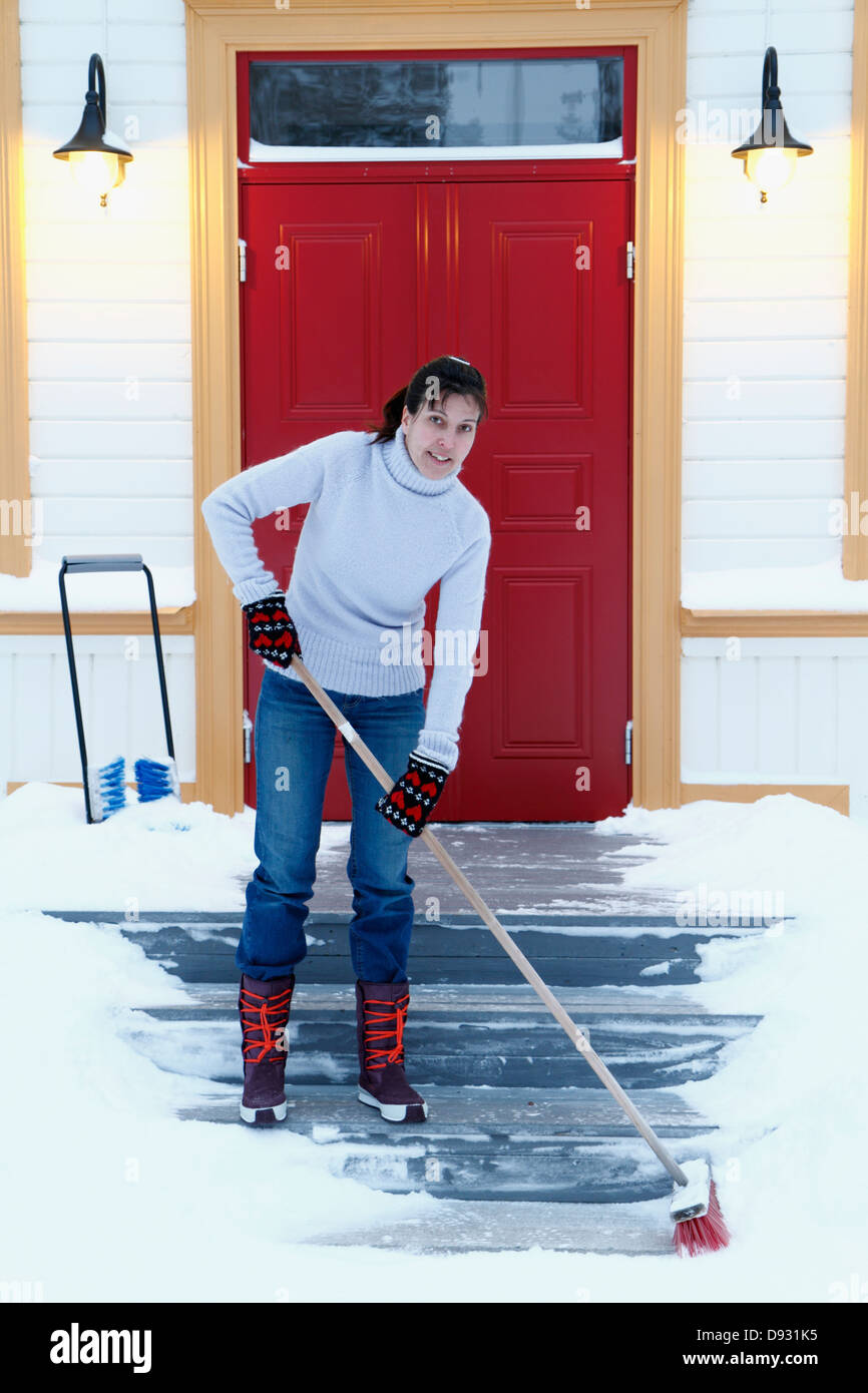 Woman removing snow from front steps Stock Photo
