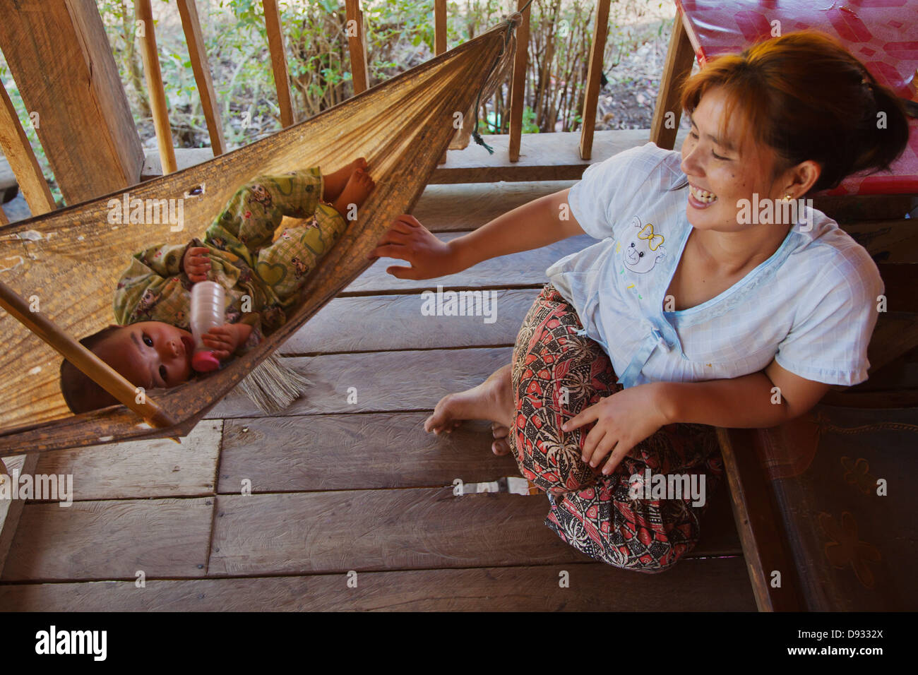 A mother rocks her baby in a SHAN VILLAGE near KENGTUNG also known as ...