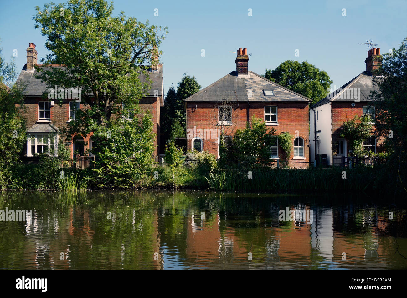 Period houses overlooking the village pond and reflecting in the water. Ashtead, Surrey, England, UK. Stock Photo
