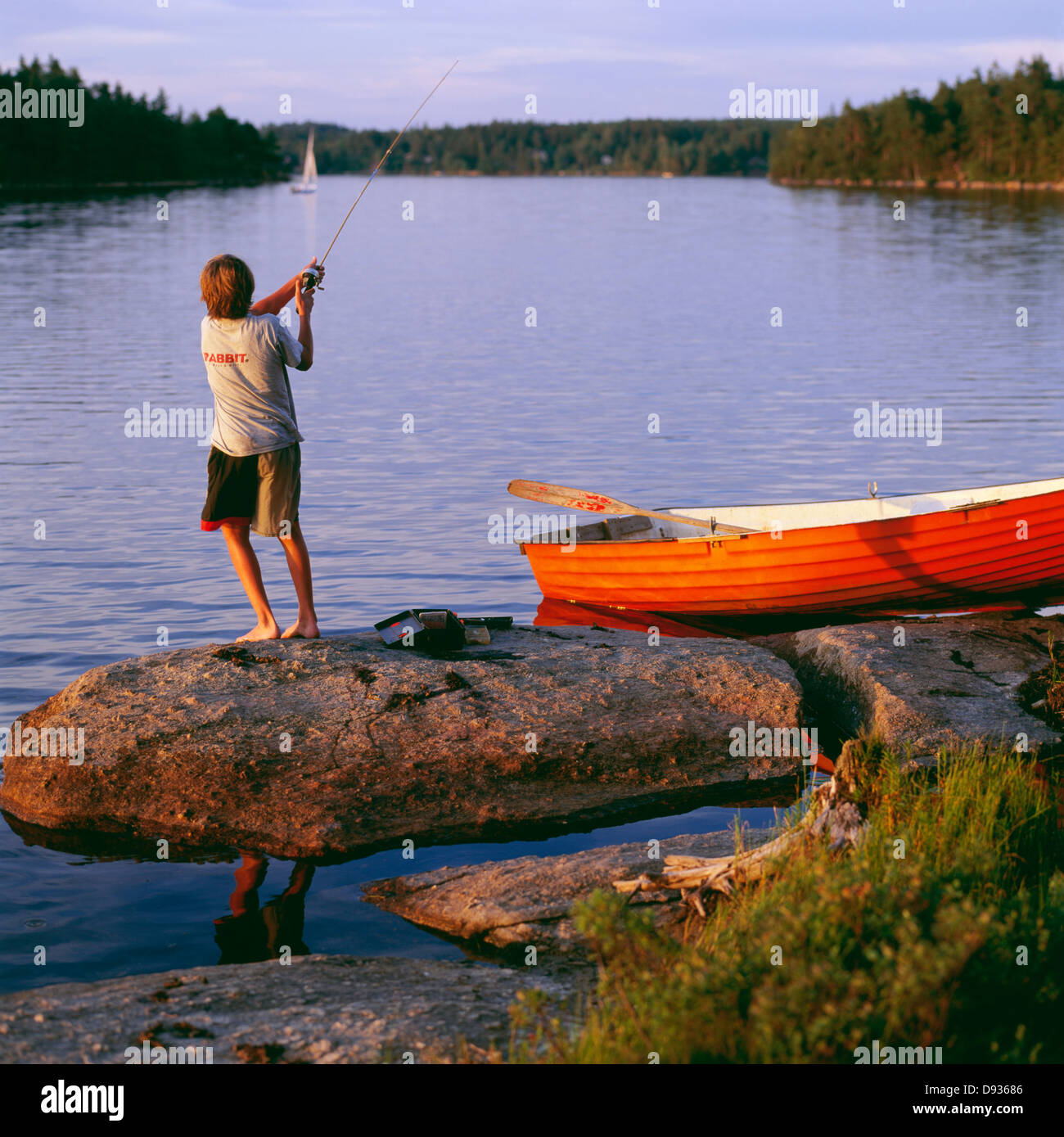 Boy fishing by boat, rear view Stock Photo