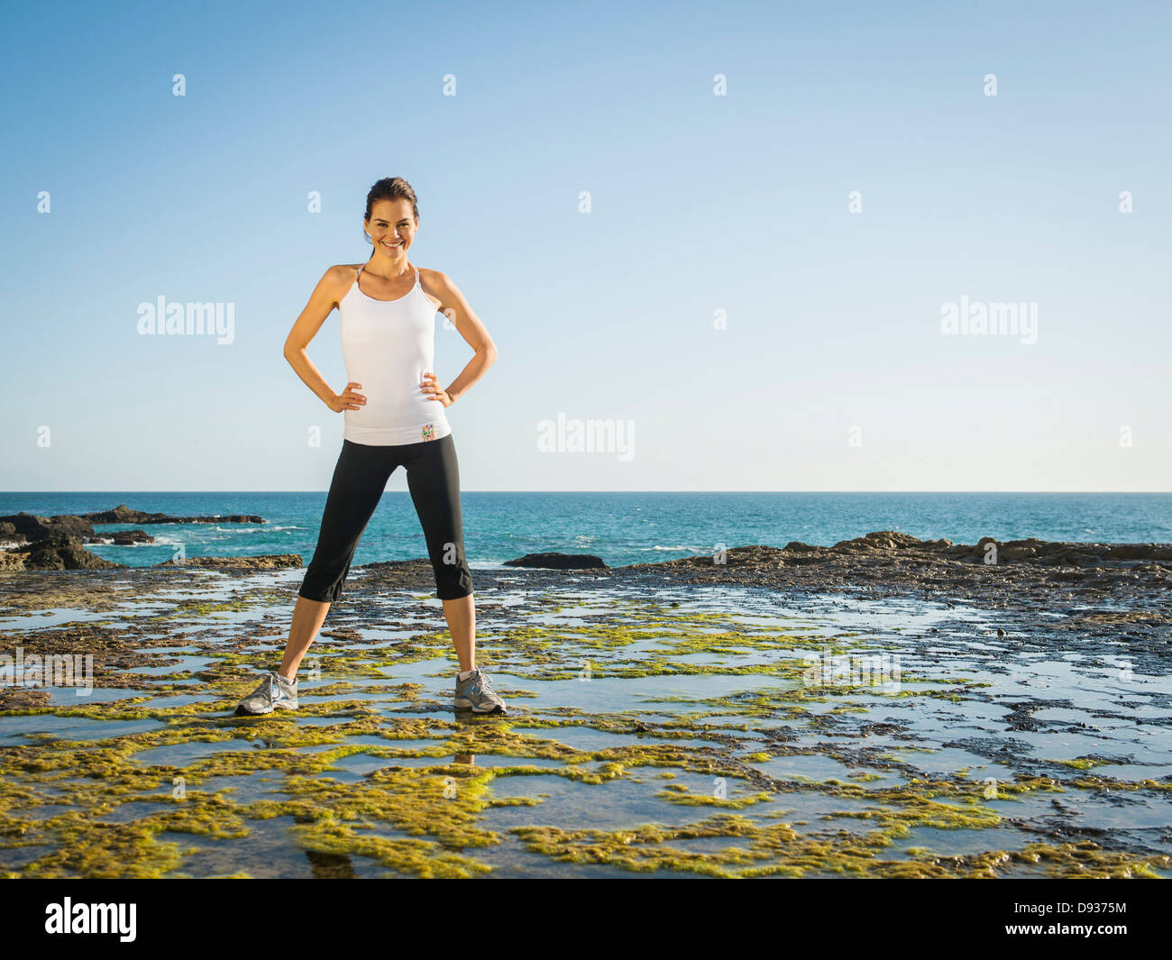 Mixed race runner standing on rocky beach Stock Photo