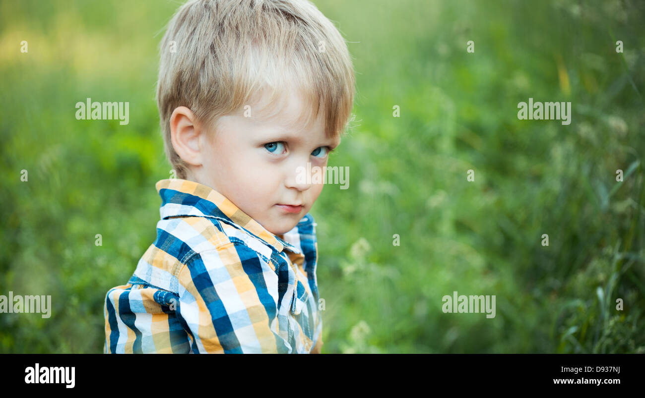 A cute little boy in a field of green grass in the park Stock Photo