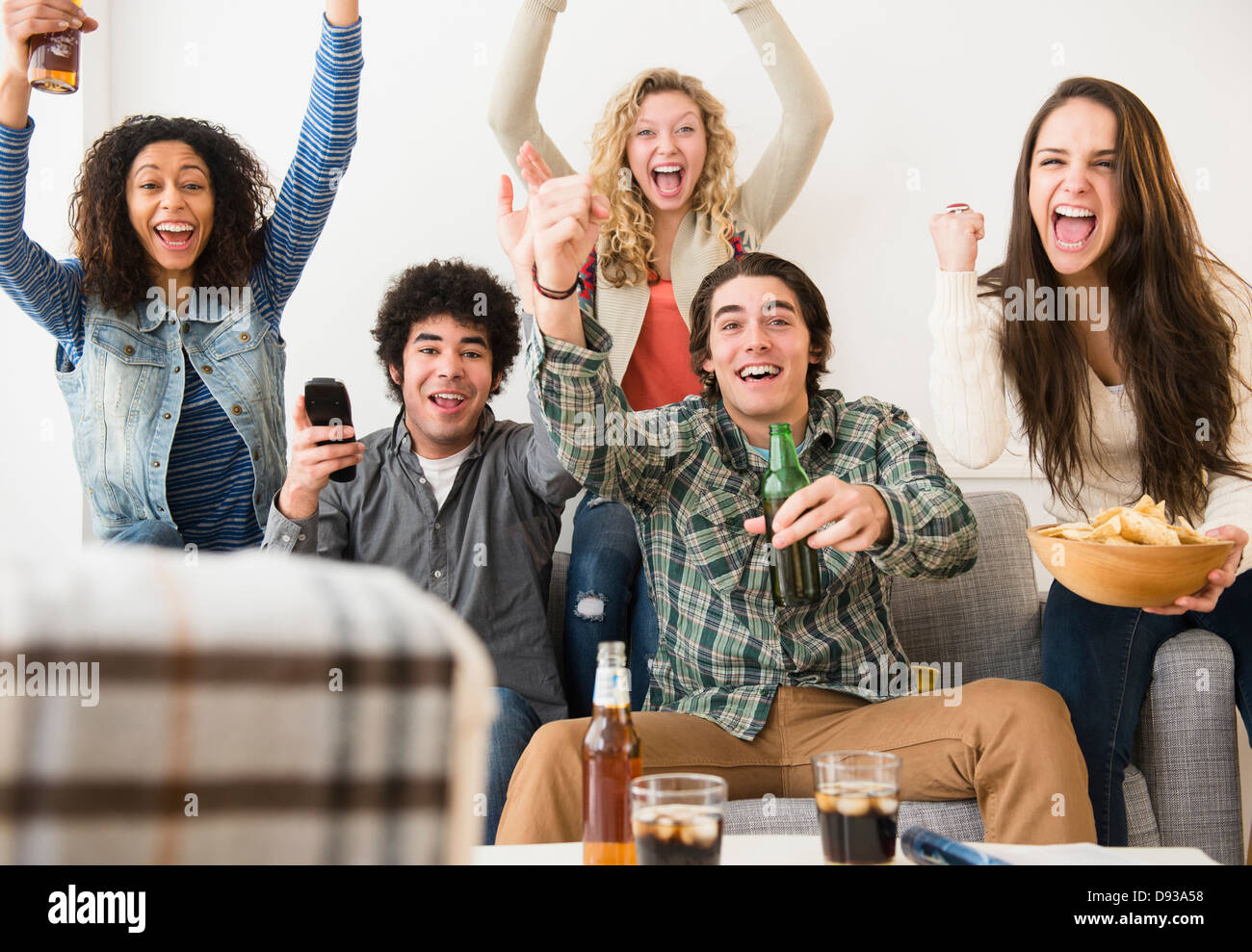 Friends cheering in living room Stock Photo