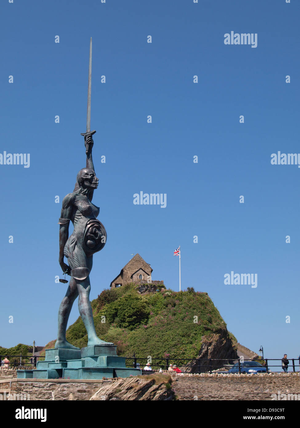 A controversial 66ft statue of a pregnant woman by artist Damien Hirst with St. Nicholas chapel behind, Ilfracombe , Devon . Stock Photo