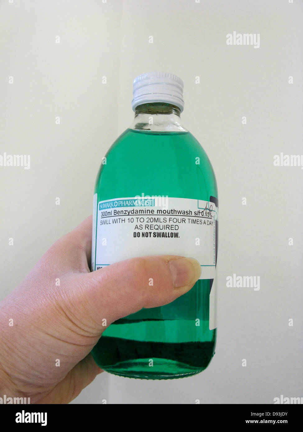 Woman with a bottle of Benzydamine mouthwash to relieve mild to