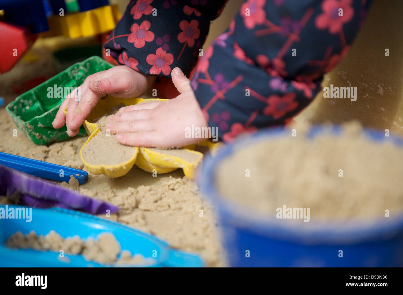 A child plays in a sandpit making sand castles with moulds Stock Photo