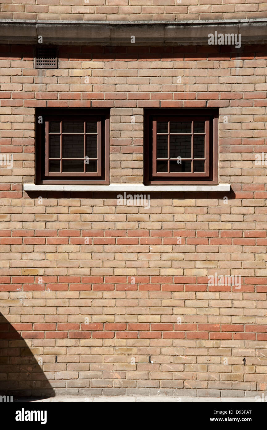 Two windows in a red and tan brick wall Stock Photo