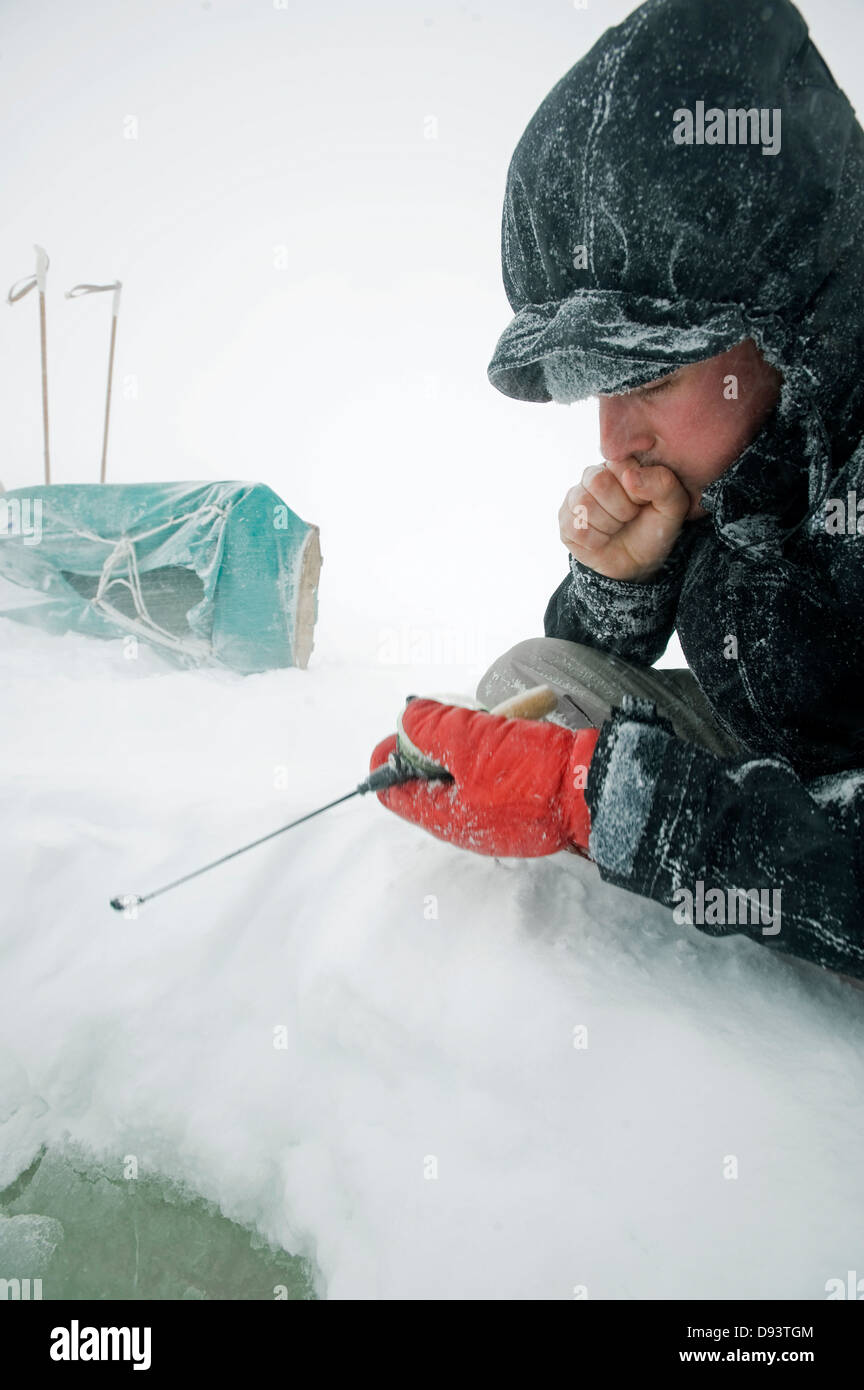 Man ice fishing in frozen lake Stock Photo Alamy