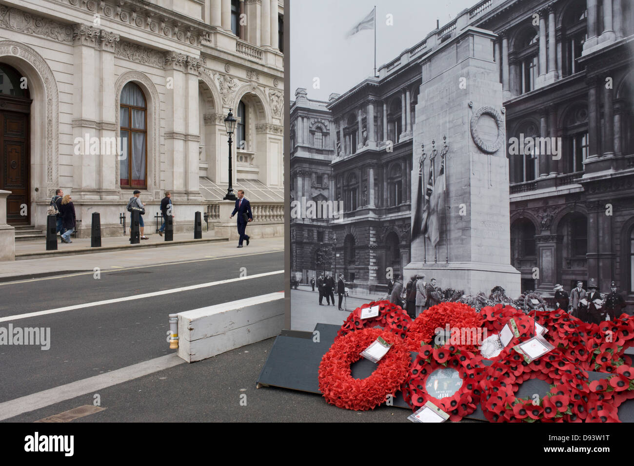 Real remembrance wreaths on the ground at the foot of a black and white vintage era photograph that shows the Cenotaph, currently hiding the real monument being renovated in London's Whitehall. In a landscape of false perspective and confusing juxtapositions between reality and the reproduction of the picture, we see the famous war memorial in central London. Stock Photo