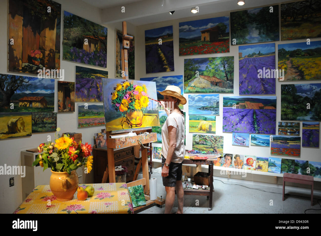 Female artist painting still life subjects in studio surrounded by her artwork at studio in Laguna Beach, California Stock Photo