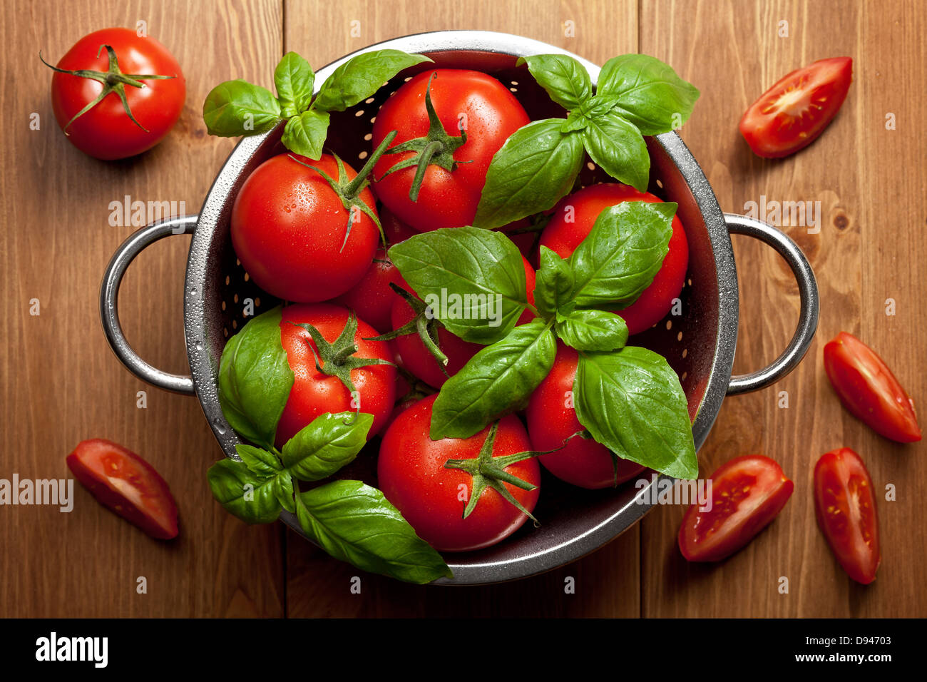 Tomatoes with basil in colander on wooden table background. Food ...
