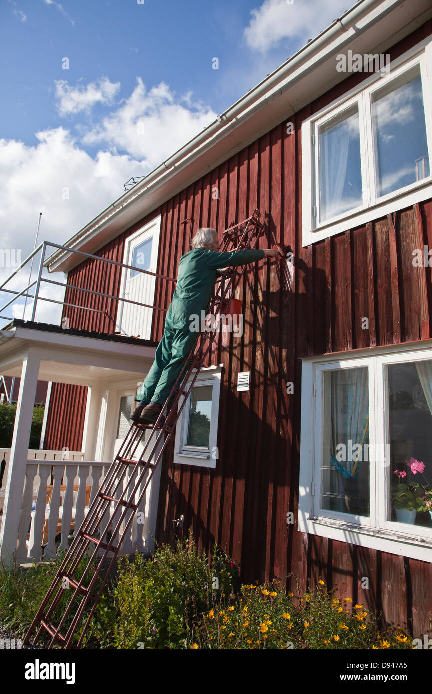 Man standing on ladder and painting cottage house Stock Photo - Alamy