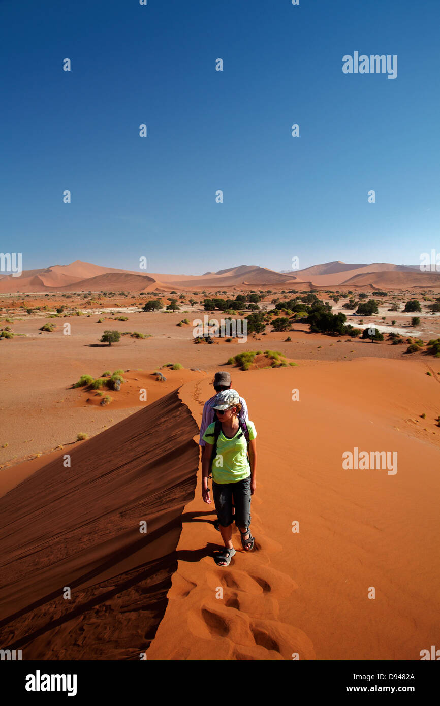 Family climbing sand dune at Sossusvlei, Namib-Naukluft National Park ...