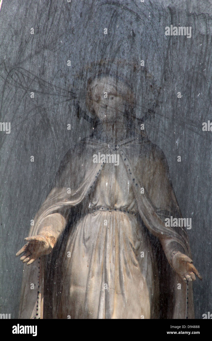 female religious statue in street side altar by church in rome italy