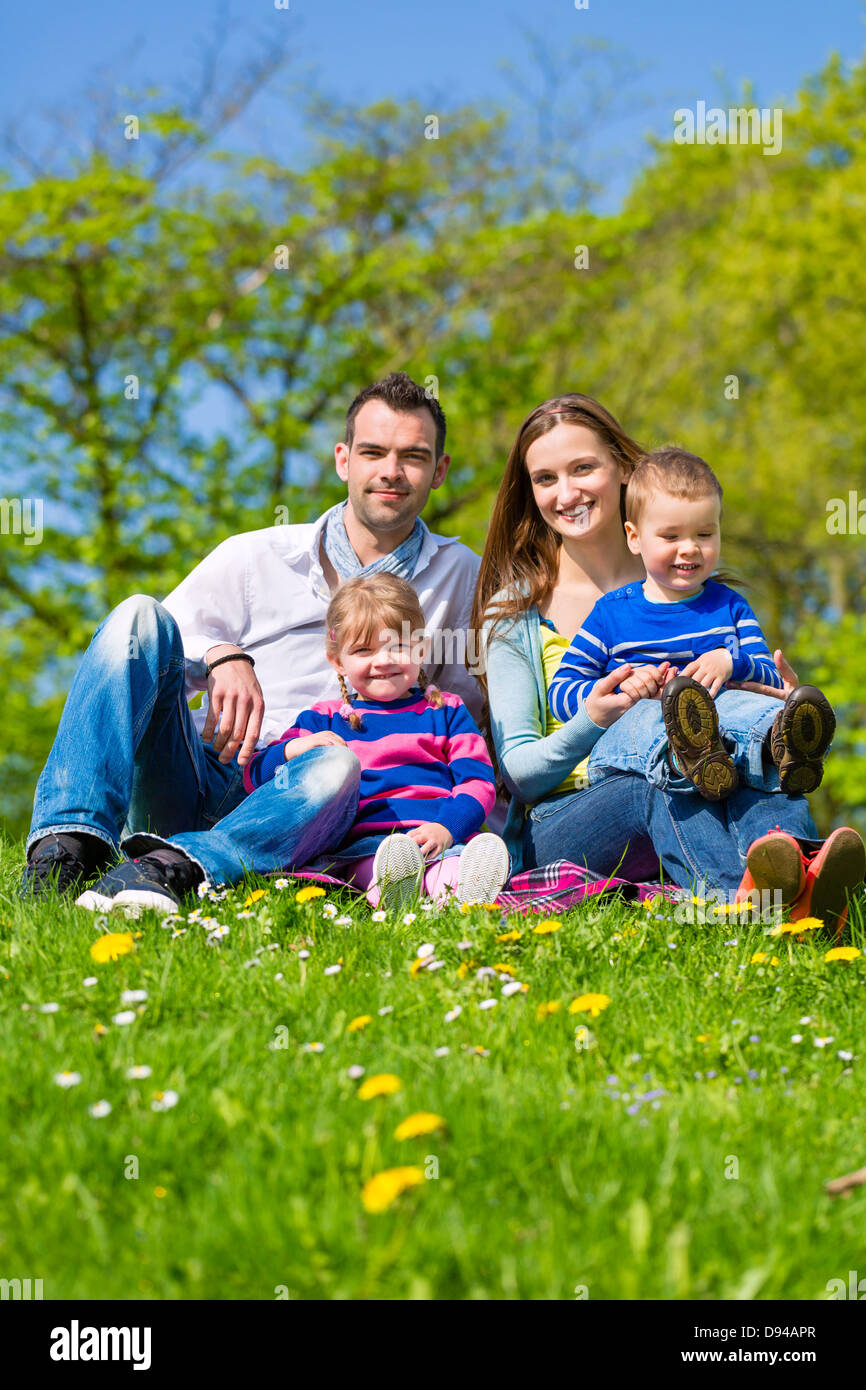 Happy family with daughter and son sitting in a meadow in summer Stock Photo