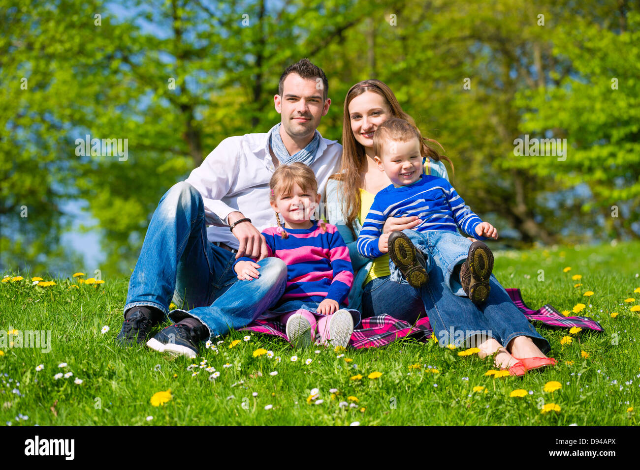 Happy family with daughter and son sitting in a meadow in summer Stock Photo