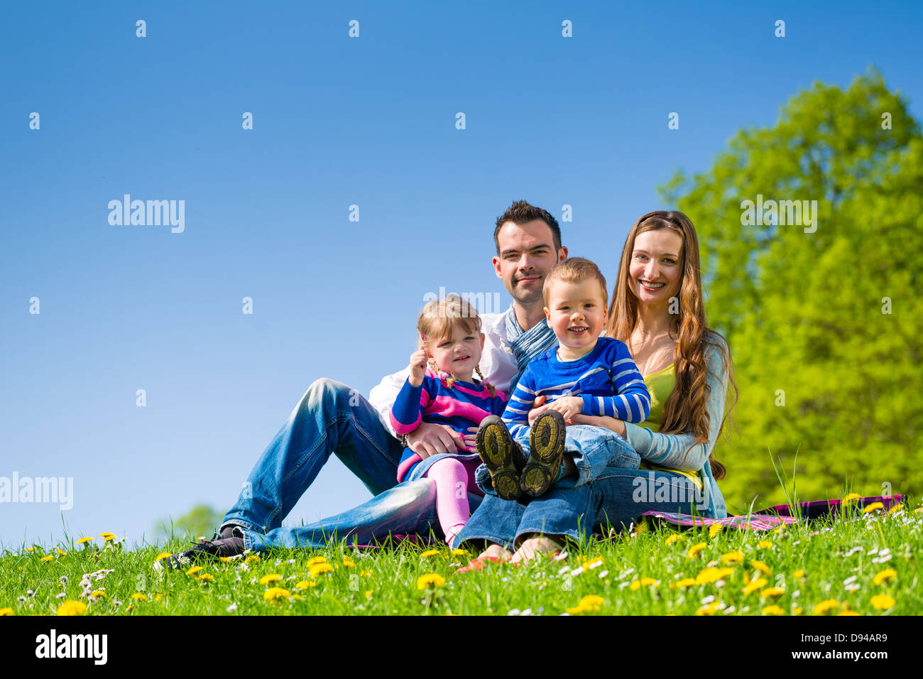 Happy family with daughter and son sitting in a meadow in summer Stock Photo