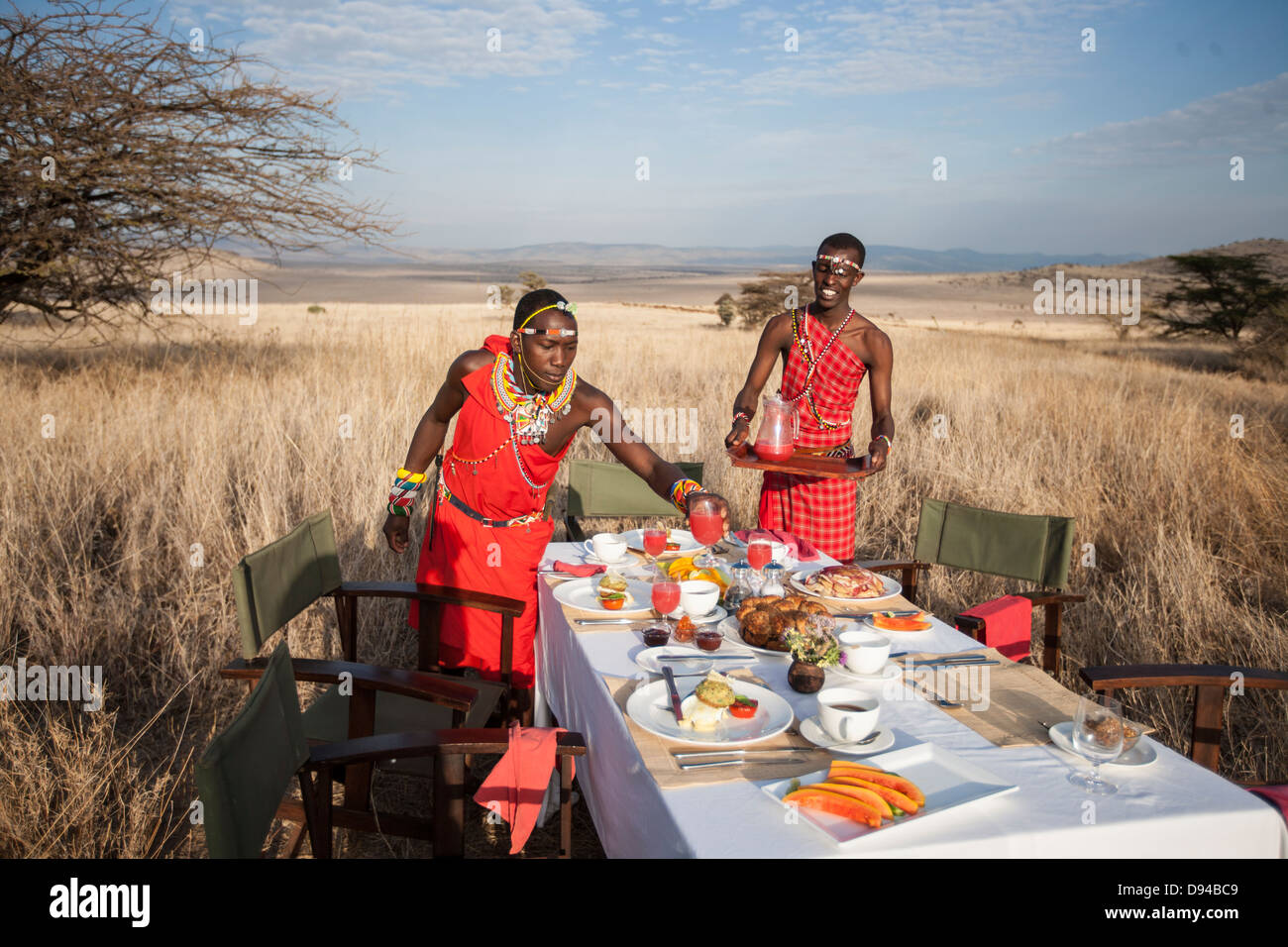 two Maasai tribesman setting breakfast table on safari tour Stock Photo