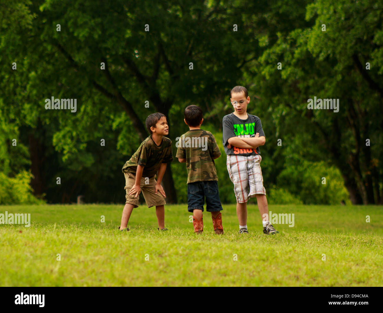 Three young boys play in a field after a rain storm Stock Photo - Alamy