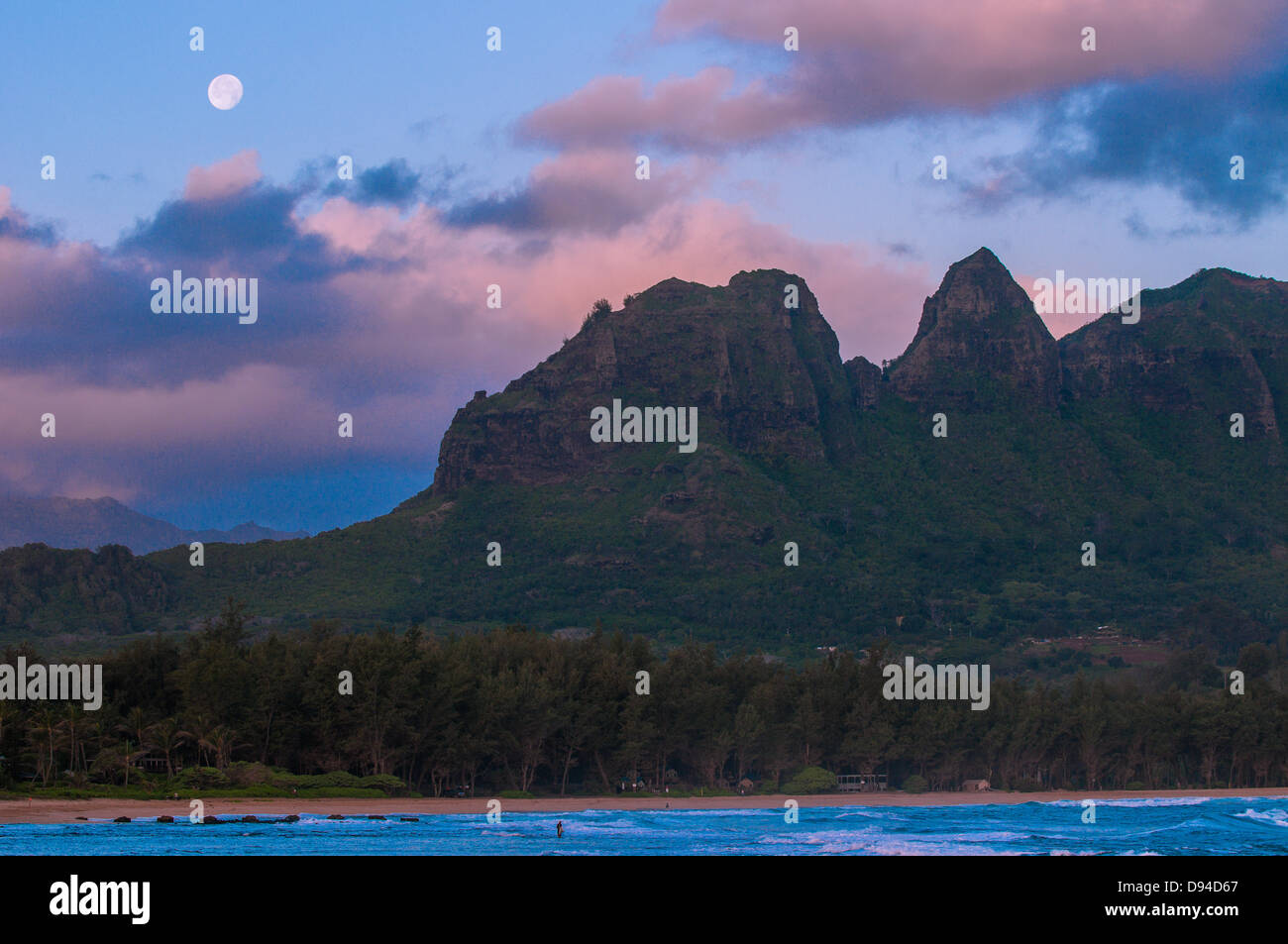 Net fisherman on the reef at dawn as the moon sets behind the Anahola Mountains, Kauai, Hawaii Stock Photo