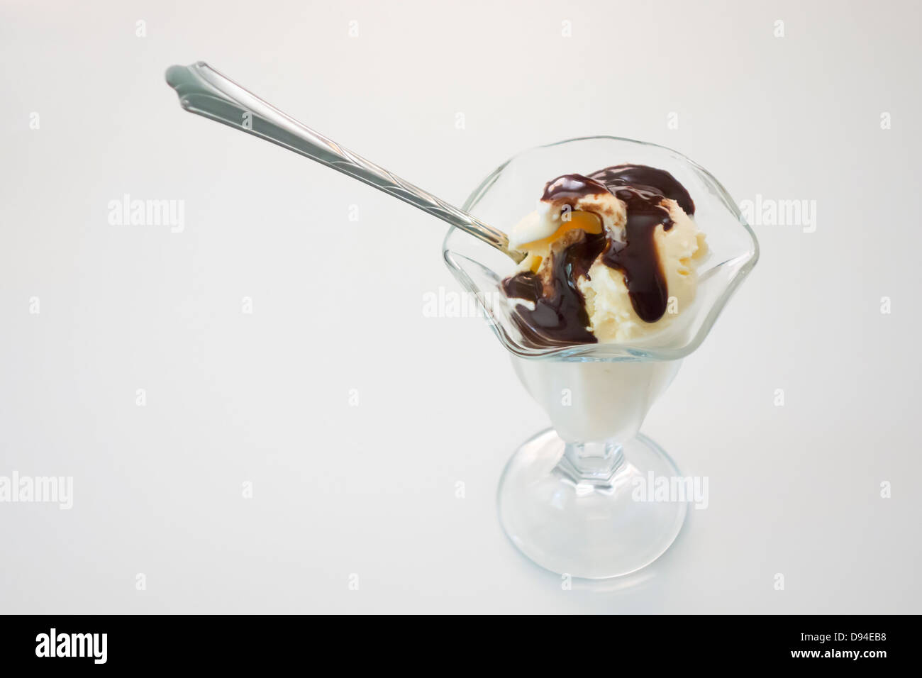 Vanilla ice cream with chocolate syrup in a dessert glass against a white background. Taken from above. Stock Photo