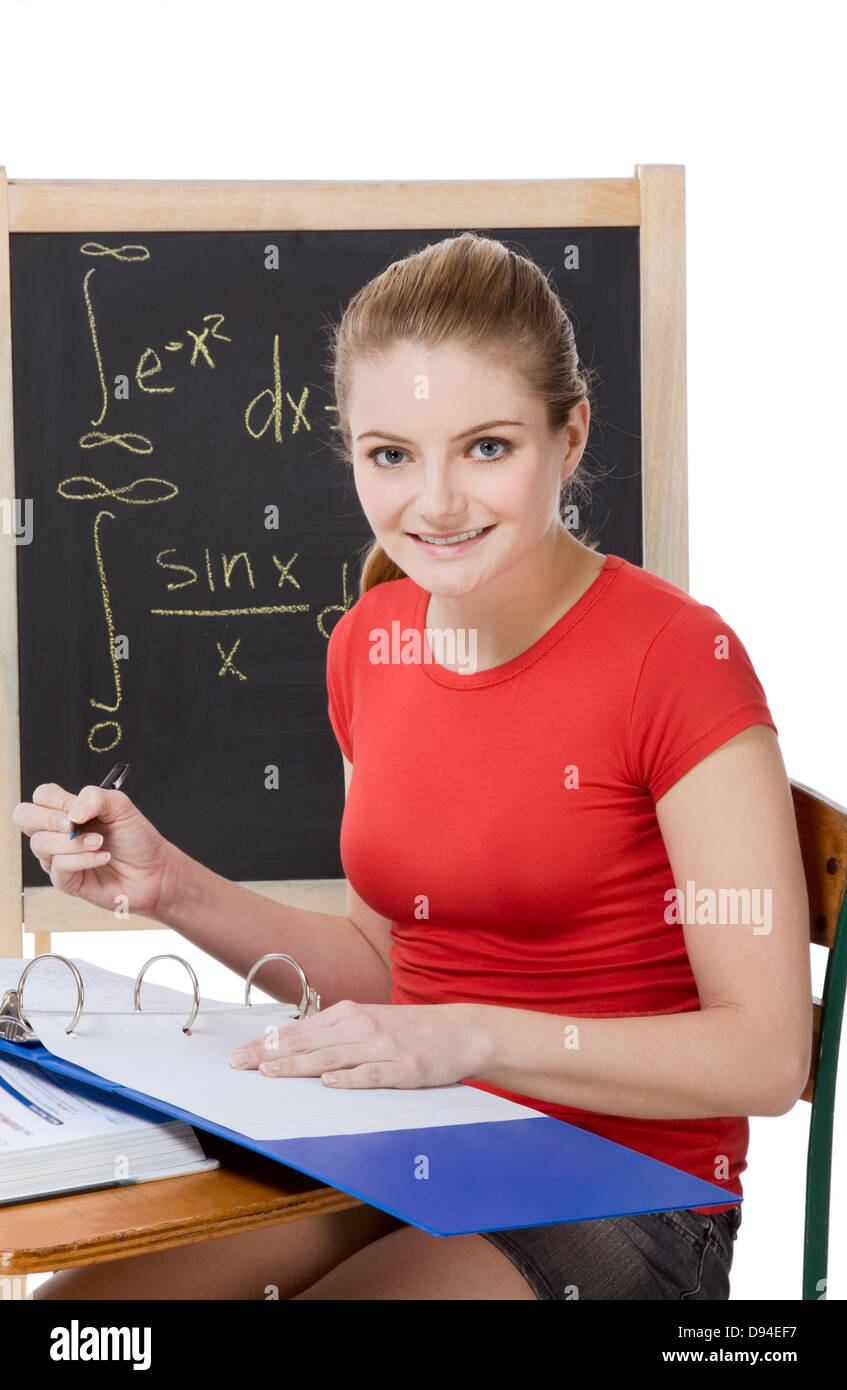University college student sitting by desk at math class. Blackboard with advanced mathematical formulas visible in background Stock Photo