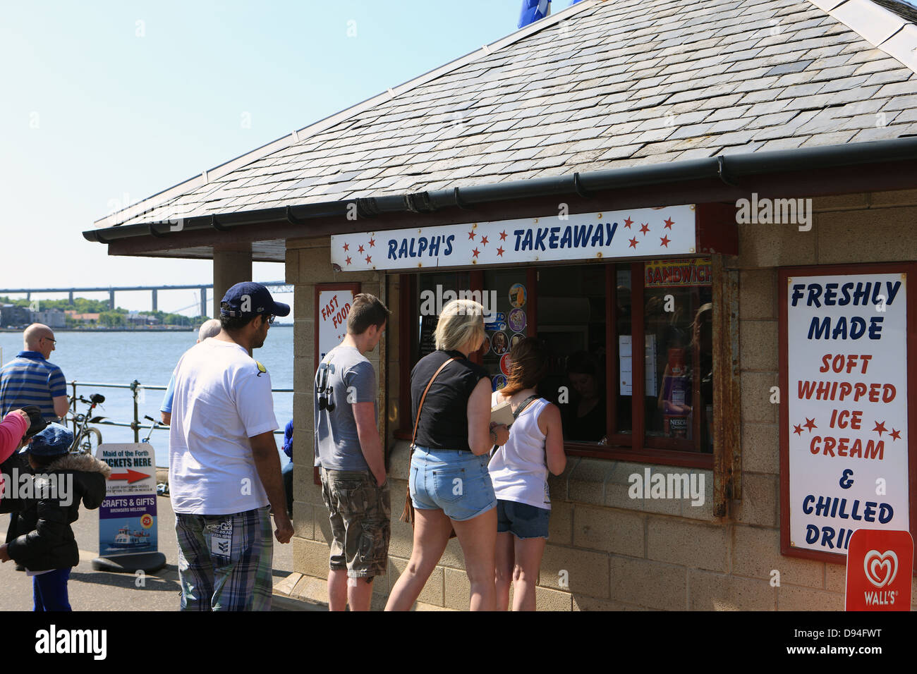 Queue at a takeaway shop on the waterfront at South Queensferry with the Forth Road Bridge in the background Stock Photo