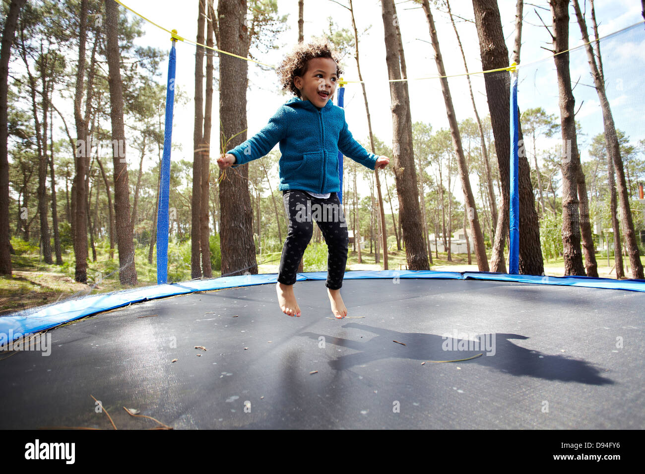 Mixed race girl jumping on trampoline Stock Photo