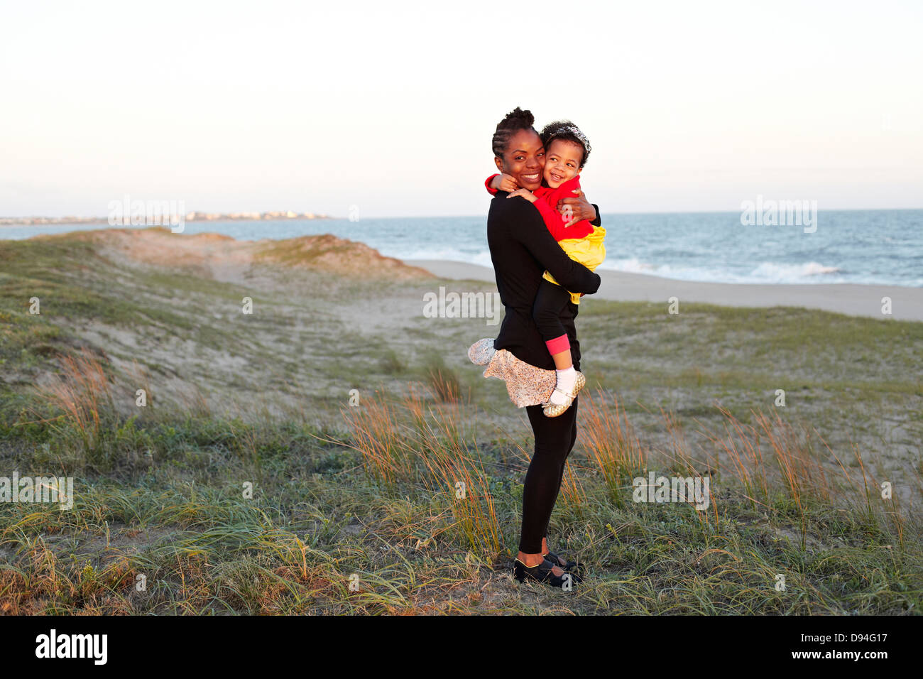 Mother hugging daughter on beach Stock Photo