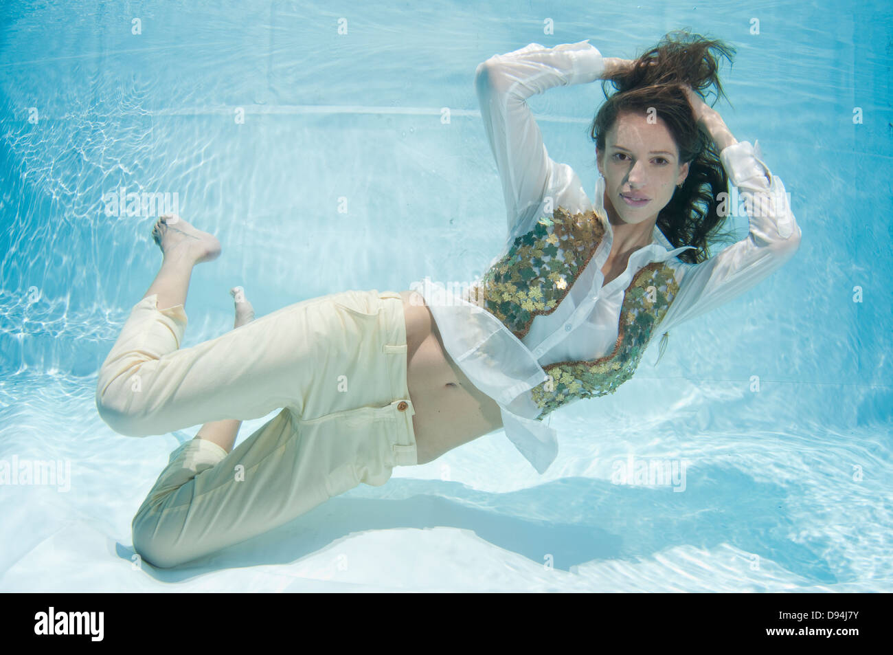 A young trendy dressed woman floats underwater Model release available Stock Photo
