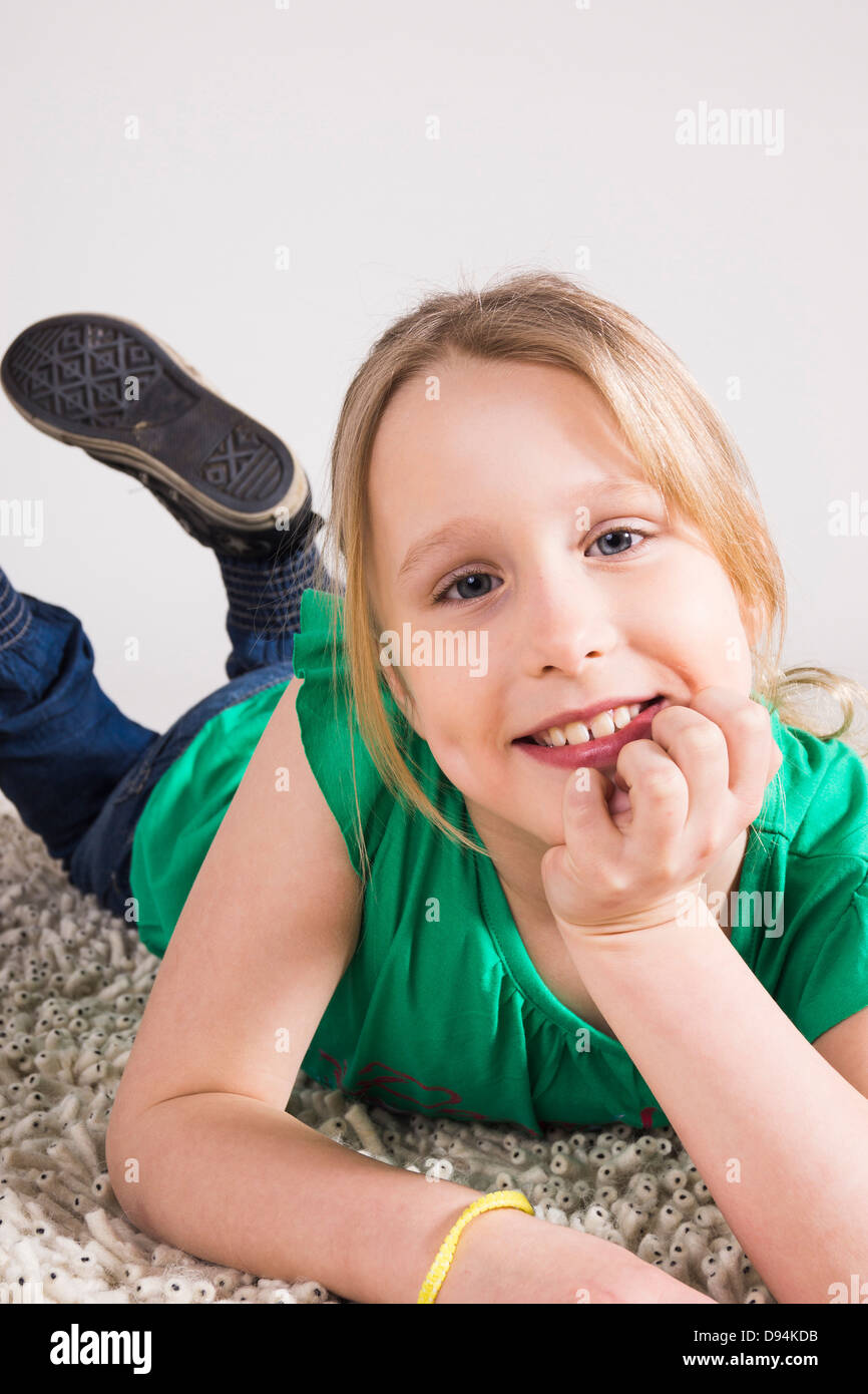 Portrait of Girl leaning on Hand and Lying on Stomach in Studio Stock Photo