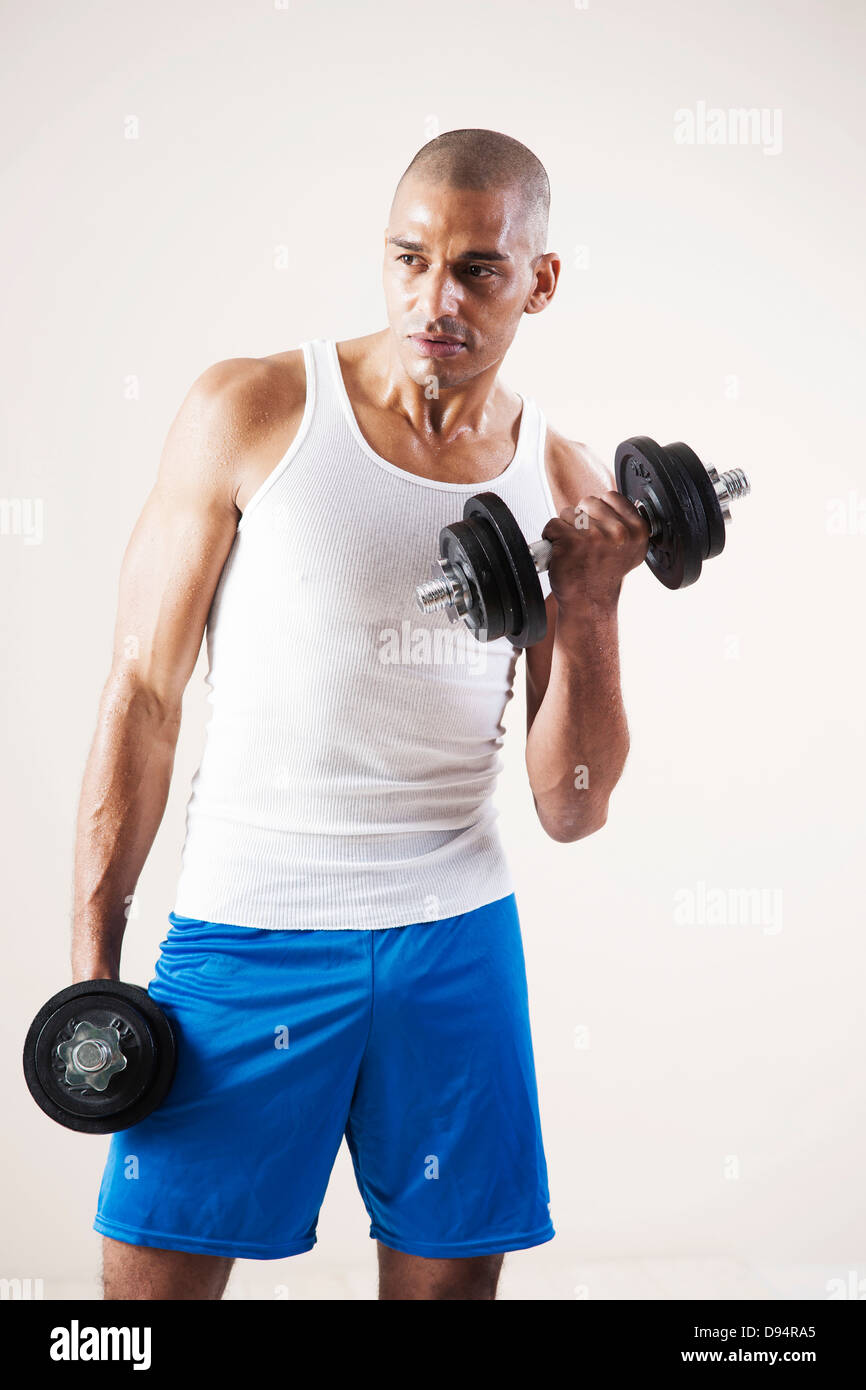 Man Wearing Work Out Clothes and Lifting Weights in Studio with White