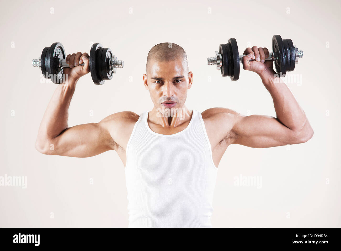 Man Wearing Work Out Clothes and Lifting Weights in Studio with White