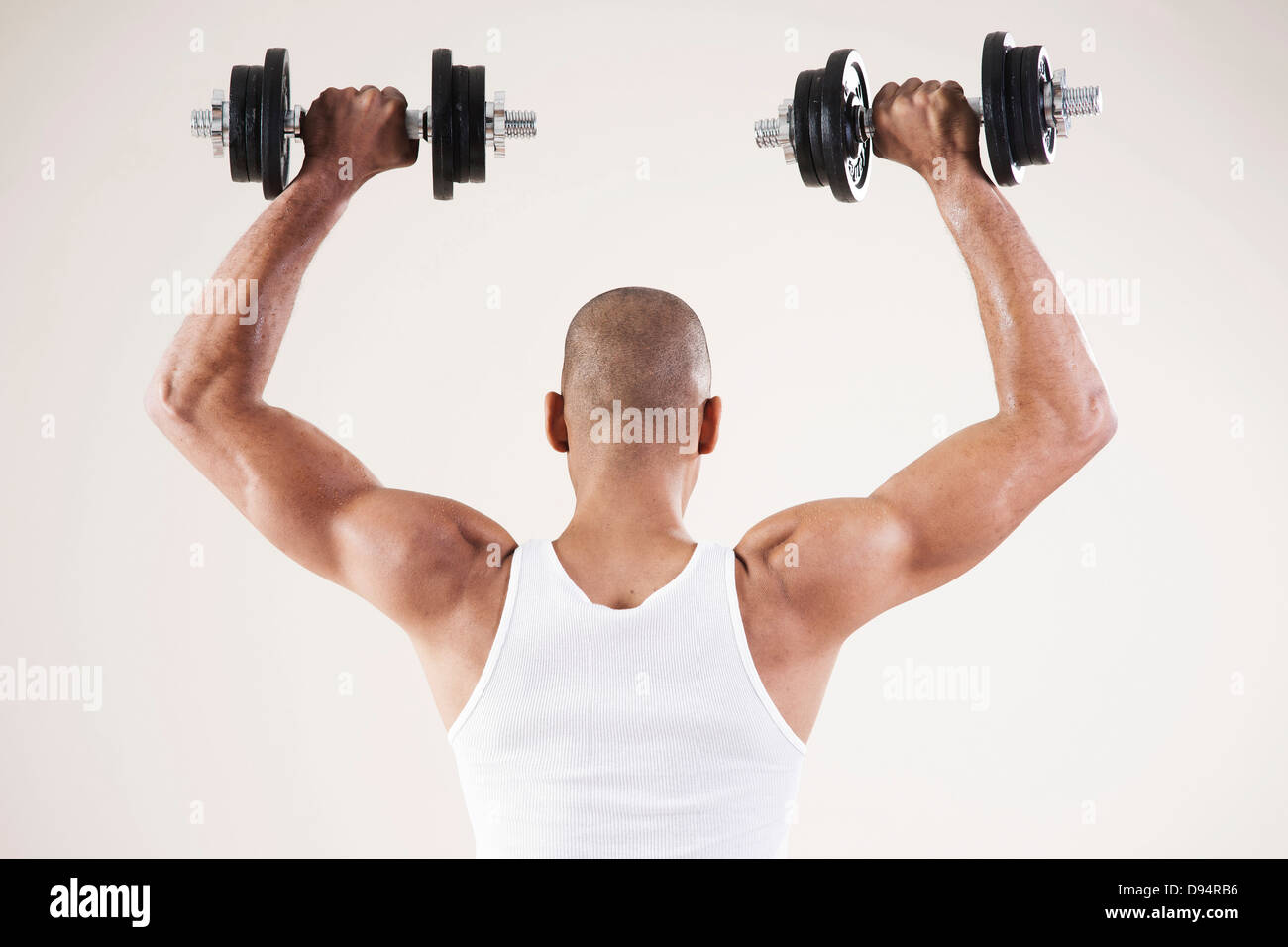 Man Wearing Work Out Clothes and Lifting Weights in Studio with White