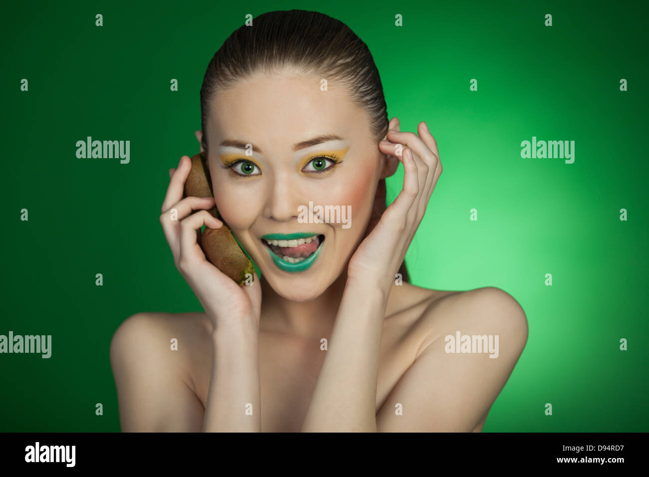 Beauty portrait of a girl with kiwi on a green background Stock Photo ...
